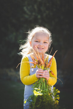Young girl holding freshly harvested garden vegetables