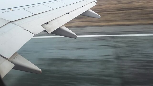 Airplane wing with flaps extending, moving swiftly along the tarmac, capturing the dynamic moment before flying and symbolizing ready for travel or journey