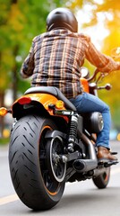 Naklejka premium A motorcyclist wears a black helmet, plaid shirt, and jeans while riding an orange cruiser on an asphalt road