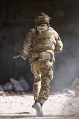 Fototapeta premium Soldier in Camouflage Tactical Gear Running Through Dusty Building During Urban Military Training Operation