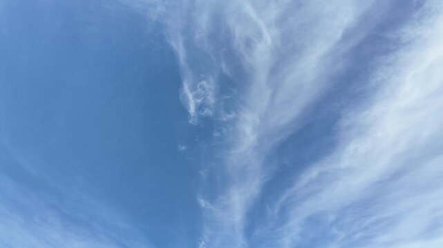 Pale blue sky with wispy white cloud slow pan.