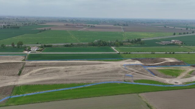 Large scale logistics construction site near Fiorenzuola d Arda with earthworks, internal roads and development plots within flat Po Valley landscape close to major highway A1 junction