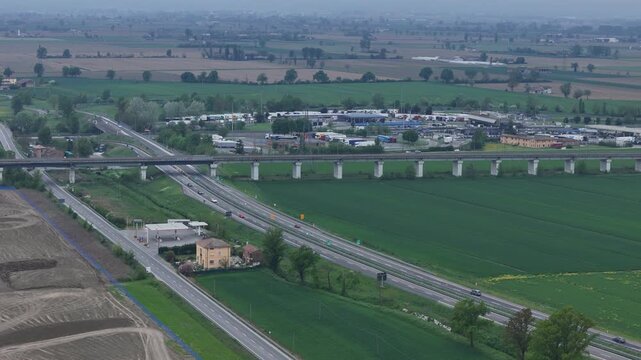 Transport hub near Fiorenzuola d Arda Piacenza Emilia Romagna Italy with SS9 Via Emilia, Autostrada A1 and A21, Milano Bologna railway viaduct and Autogrill service area within Po Valley farmland