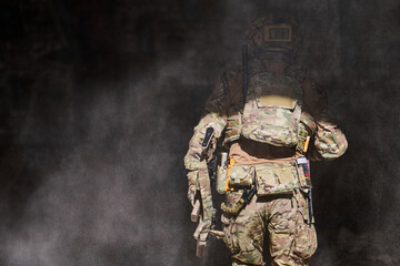 Obraz premium Armed Soldier in Camouflage Tactical Gear Walking Through Dusty Smoke During Military Operation