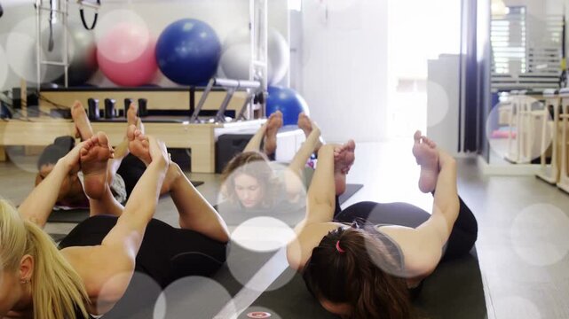 Pair holding bow pose on cue in pilates, bokeh over participants and mats, boosting spine strength