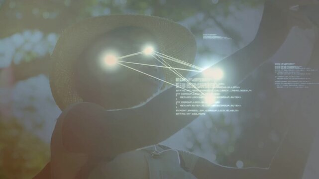 Woman raising smartphone under tree canopy, initiating AR nodes linking hat, face, arm for mapping