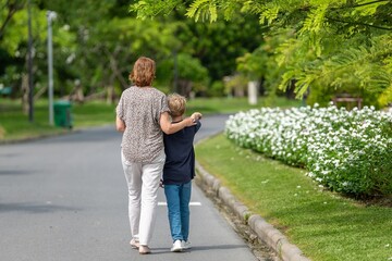 Fototapeta premium Grandmother and grandson teaching pointing sitting in flower garden loving outdoor bonding generational happy family connection. relationship family outdoor summer joyful warm sunlight