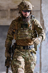 Obraz premium Bearded Soldier In Tactical Gear Walking Through Urban Combat Environment With Rifle And Helmet