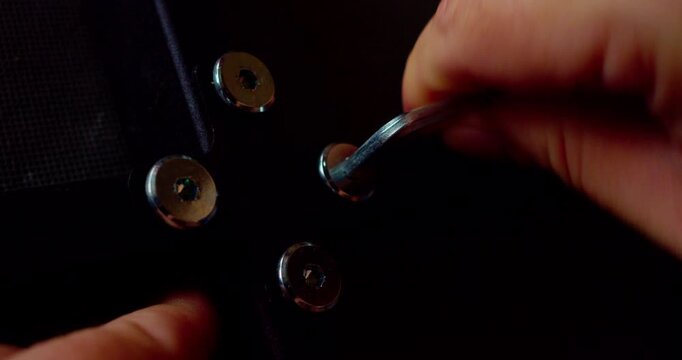 Macro shot of a hand using a specialized key to tighten a screw during mechanical assembly.
