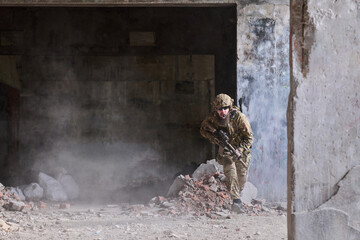 Obraz premium Soldier In Tactical Gear Moving Through Urban Ruins With Rifle During Combat Training Operation