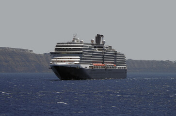 Luxury cruiseship cruise ship liner Eurodam anchoring at sea on sunny summer day during Mediterranean Greek Island Santorini caldera cruising with shore and rocky island in background © Tamme Wichmann