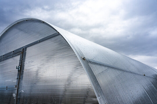 A Close-Up View of a Glimmering Greenhouse Under a Moody Sky, Showcasing Nature's Resilience and the Craftsmanship of Sustainable Agriculture