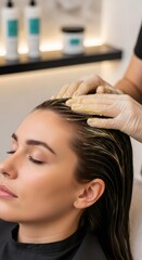 Naklejka premium Woman client receiving hair treatment from a hairstylist in protective gloves, application of hair mask for beauty concept.