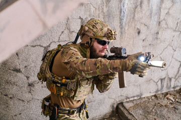 Fototapeta premium Tactical Soldier In Camouflage Aiming Rifle With Mounted Light During Urban Special Forces Operation