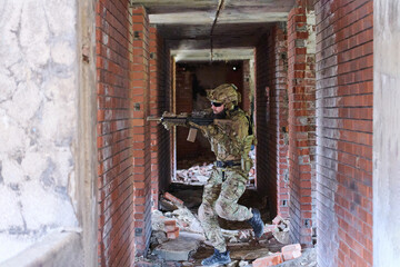 Obraz premium Soldier in Tactical Gear Clearing Rubble-Filled Corridor During Urban Combat Training Exercise