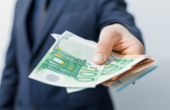 Hand offering euro banknotes, symbolizing finance, wealth, and business transactions. Concept of mon