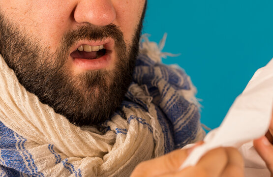 Man sneezing into a tissue, showcasing illness, allergy, and cold symptoms.