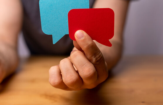 Hand holding colorful speech bubbles, discussing thoughts. Communication, idea, chat, dialogue conce