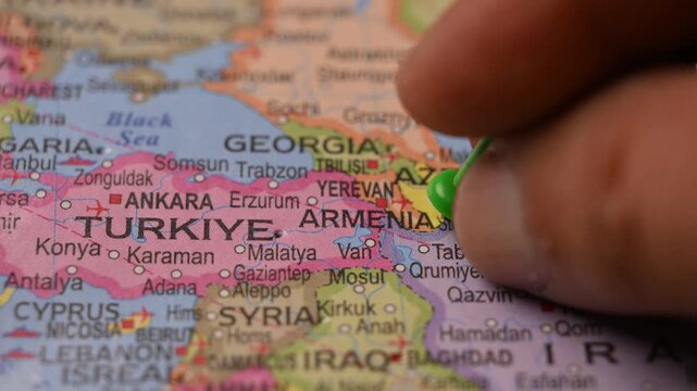 Close Up Man Pointing Green Pin on Armenia Location in Paper World Map Travel Concept