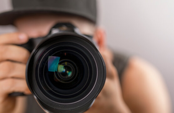 Close-up of a photographer looking through a camera lens, capturing a moment. Image reflects passion
