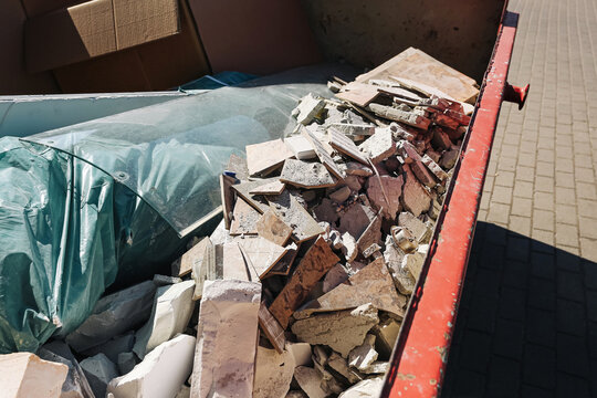 Construction dumpster waste background. Rubble debris pile scene. Renovation trash disposal concept. Broken tiles image. Building cleanup detail. Industrial container yard. Demolition site materials.