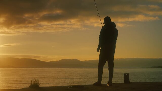Silhouette of a fisherman casting along a Norwegian shoreline at sunset, with golden light reflecting on calm water and mountains in the distance creating a cinematic scene.