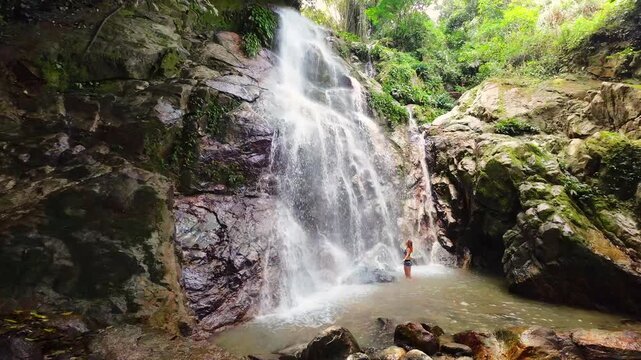 A purely emotional, slow-motion of a fit woman at the edge of Marinka Waterfalls, Minca. Standing in awe, she absorbs the powerful spray and mist in a lush tropical jungle. Spiritual oneness.