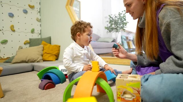 Toddler boy developing fine motor skills playing with teacher