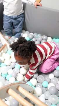 African american toddler playing in a ball pit at daycare