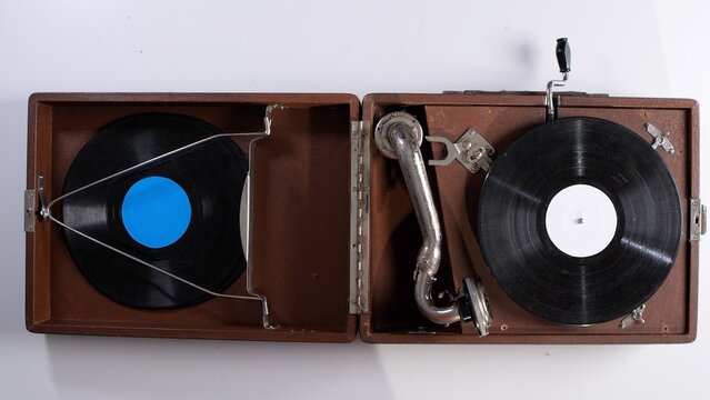 Vintage wooden suitcase phonograph with tonearm and vinyl records inside, open and ready to play  overhead studio view evoking nostalgia, music and analog charm