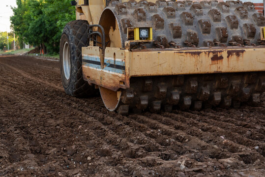 Construction worker operating a tamping rammer machine for soil compaction on site