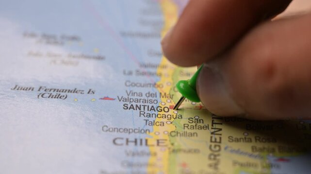 Hand Placing Green Pin on Santiago Chile Location in World Map Travel Planning Concept