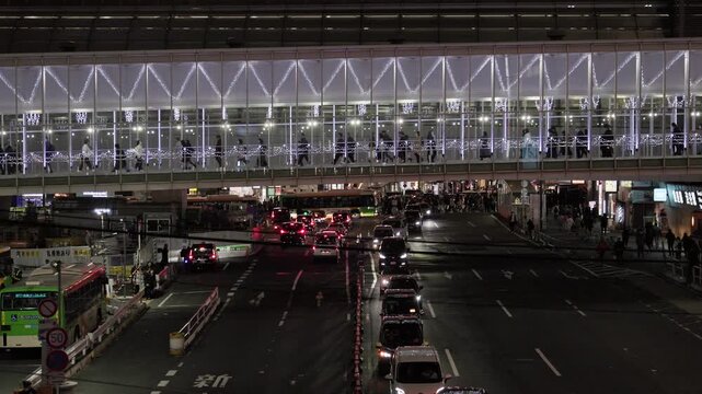 Night in Tokyo : As People Walk Along the Skyway Spanning the Urban Road of a Shopping District, Street Headlights, Intersection, and City Lights Create a Live   |  Shibuya Station, Tokyo, Japan