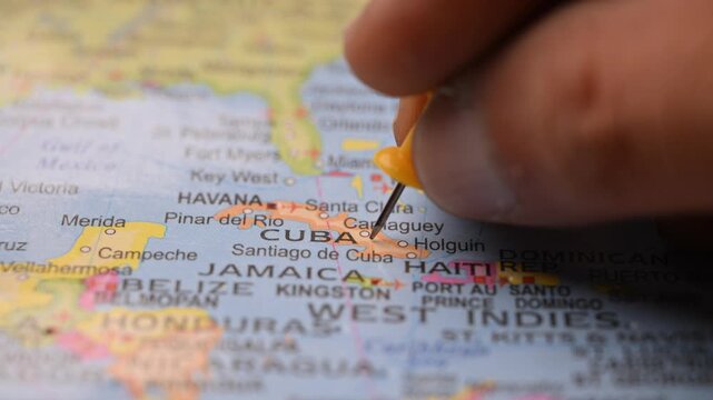 Hand Placing Yellow Pin on Cuba Location in World Map Travel Planning Concept