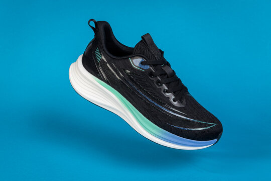 Running shoe levitating on blue background. Modern athletic footwear for fitness, sport, and training. Product photography for e-commerce and advertising.
