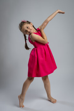 Smiling Young Girl in Elegant Pink Dress Posing in Studio. Happy Childhood Fashion Portrait, Kids Clothing, Celebration, Birthday and Family Lifestyle Concept