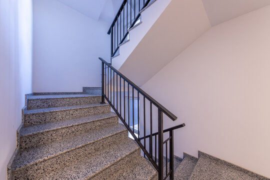 Modern stair case between floors. Stairs with metallic rail in modern building. Interior of a contemporary apartment or office building. Architecture and real estate background.
