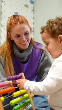 Young teacher helping toddler learn with abacus