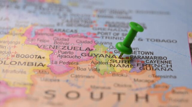 Close Up Travel Concept of Hand Placing Green Pin on Guyana Location in World Map