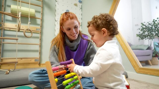 Toddler learning numbers with teacher using a colorful abacus