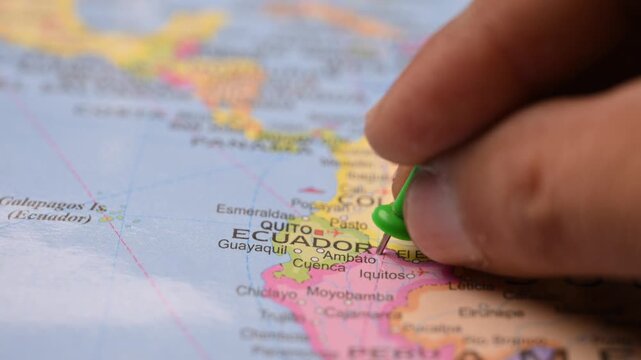 Hand Marking Ecuador with Green Pin on World Map for Travel Exploration Concept Close Up
