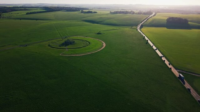 Aerial view of Stonehenge surrounded by green countryside in Wiltshire England showing the historic stone circle and rural landscape at golden hour