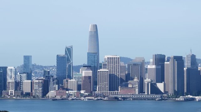 Beautiful morning aerial view of the San Francisco downtown skyline and financial district, with the iconic Salesforce Tower and city skyscrapers reflecting on the calm waters of the bay