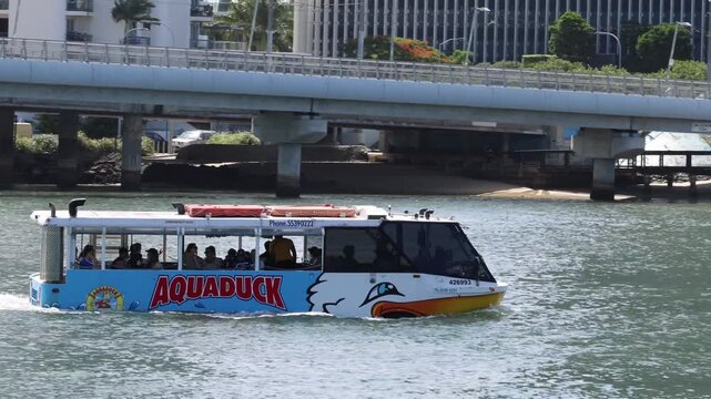 Aquaduck boat moving through water in Gold Coast Australia with passengers on board on a sunny day.