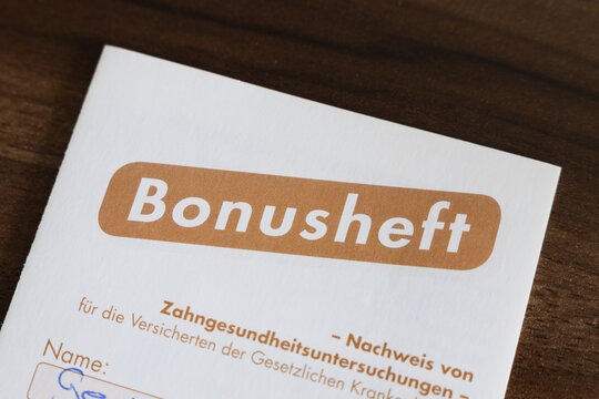 Bonusheft (bonus booklet) of the statutory health insurance in Germany. Proof of regular check-ups of the teeth by the dentist. Close-up of the front cover lying on a table.