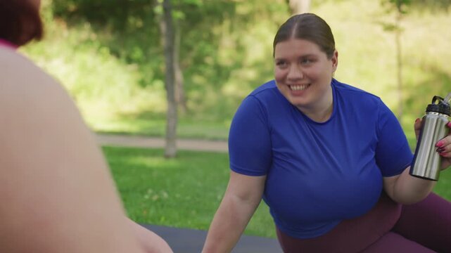 Happy curvy woman sharing weight loss results with friend after training