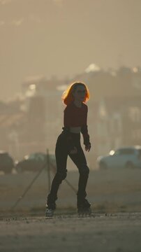 Young woman with orange hair rollerblading during a golden sunset