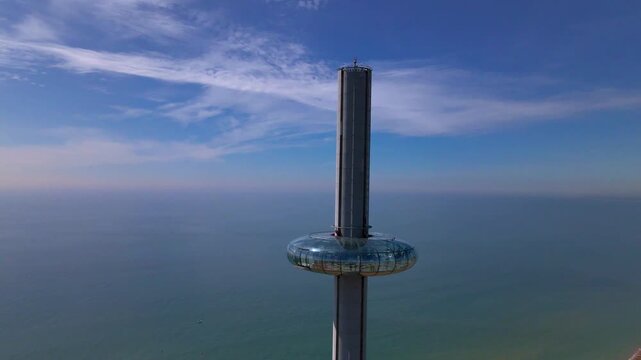 Close up aerial orbit of Brighton i360 observation pod with changing backdrop