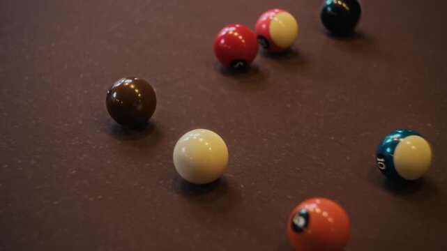 High angle close up shot of unrecognizable man lining up shot then striking cue ball during billiards game on brown felt table at pool club