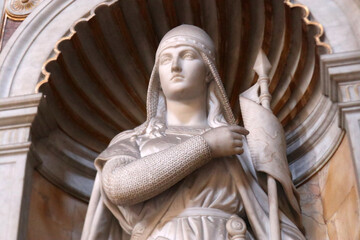 Statua in marmo di figura femminile guerriera con elmo e lancia posizionata all'interno di una nicchia monumentale a forma di conchiglia